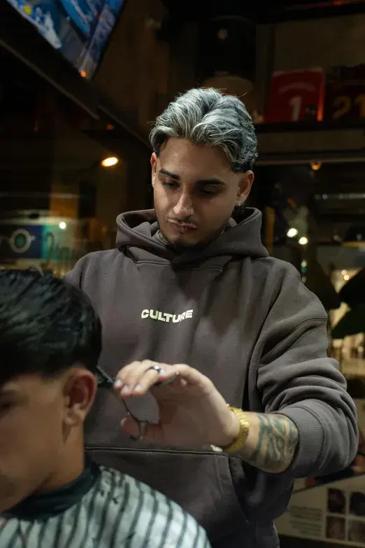 Barbero con mechas platino haciendo un degradado con máquina