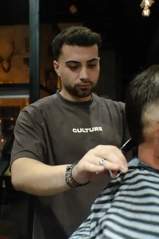 Barbero perfilando un corte con tijera y peine