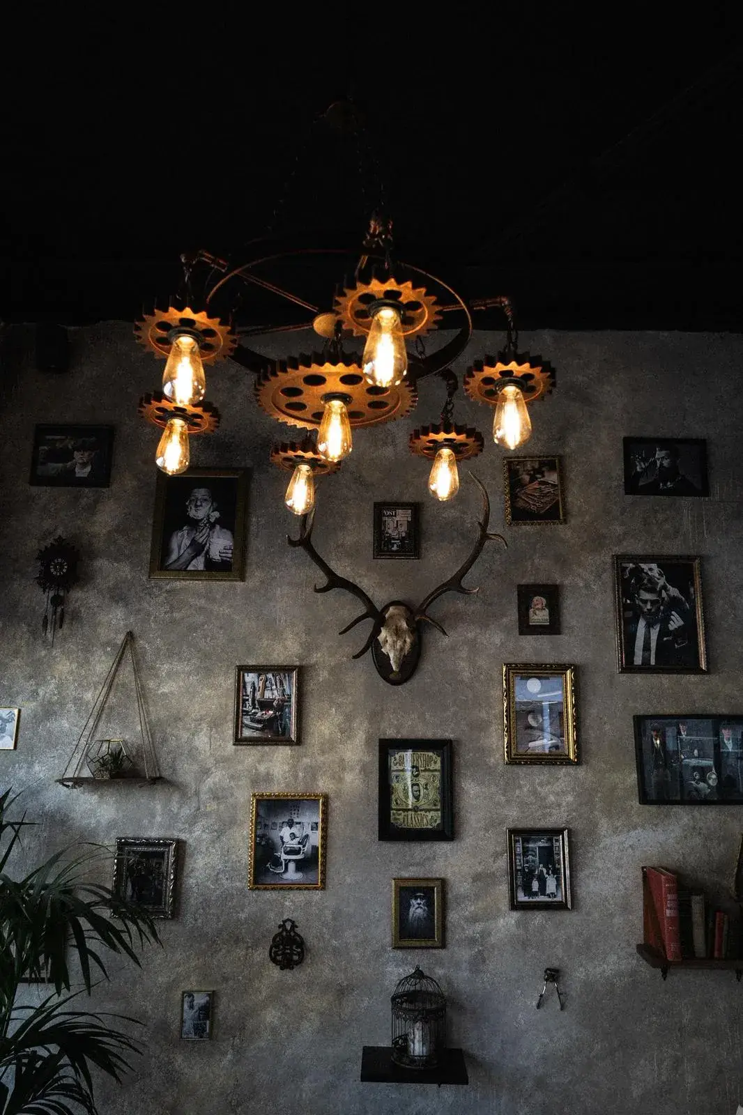 Pared de cuadros y lámpara industrial de engranajes en Culture Barber