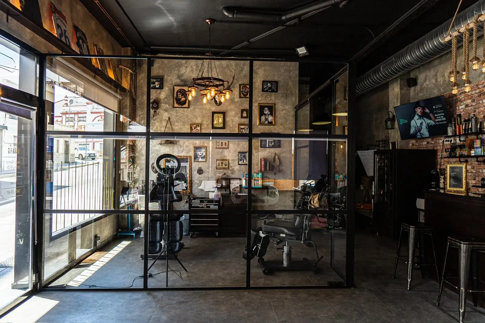 Vista general de la barbería con cristalera y pared de cuadros